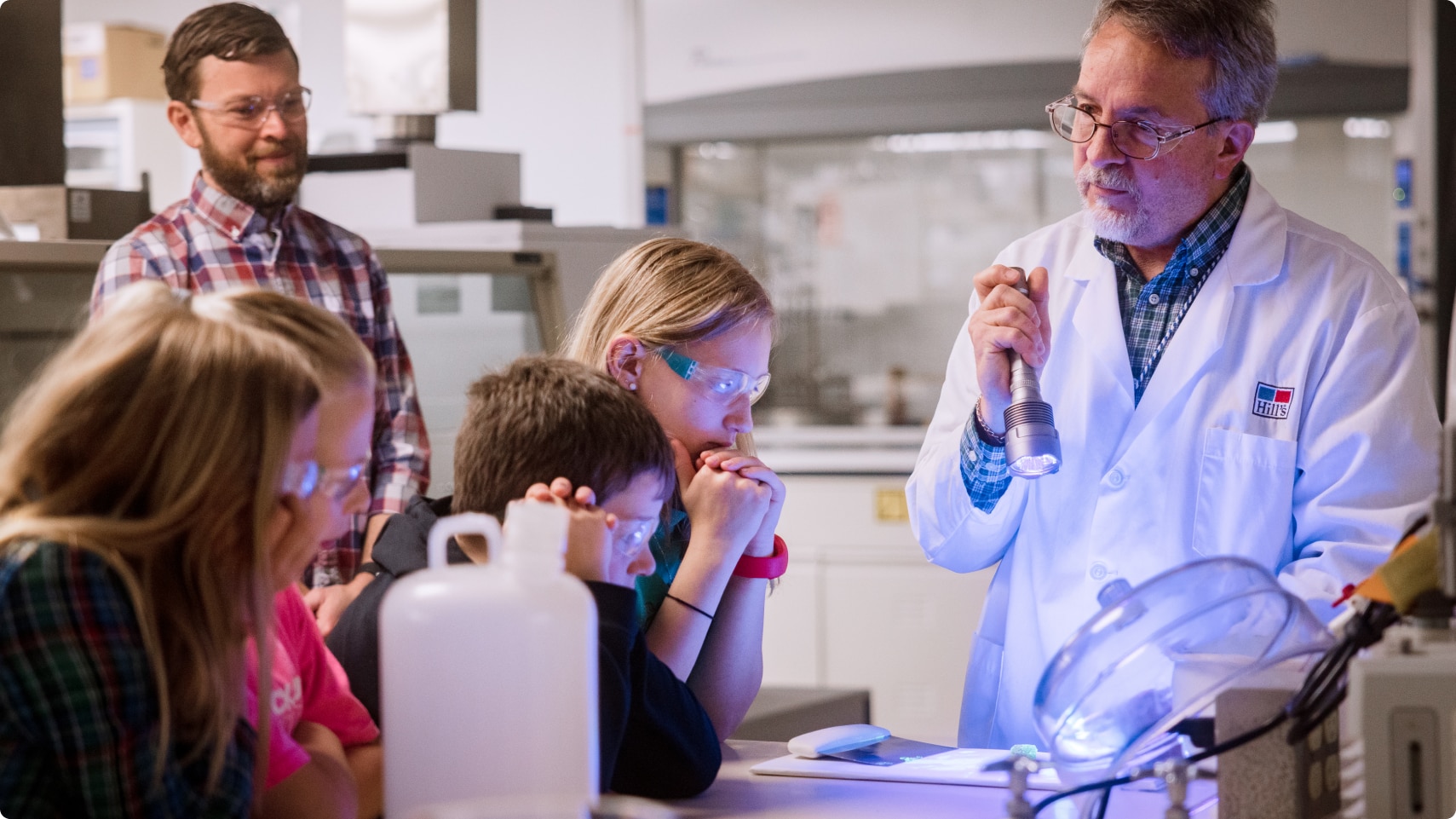 Membre de l’équipe de recherche du Centre mondial de nutrition animale montrant le laboratoire de recherche à un groupe d’enfants