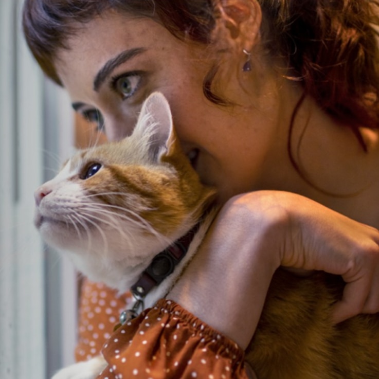 Femme portant un chandail orange et tenant un chat